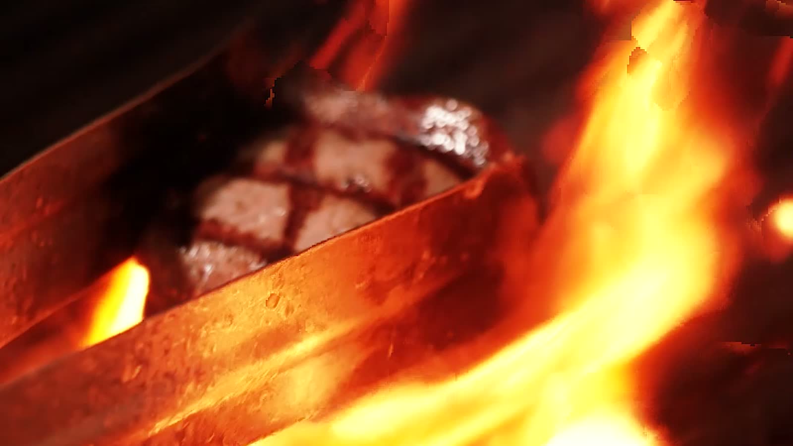 A steak searing over an open flame grill